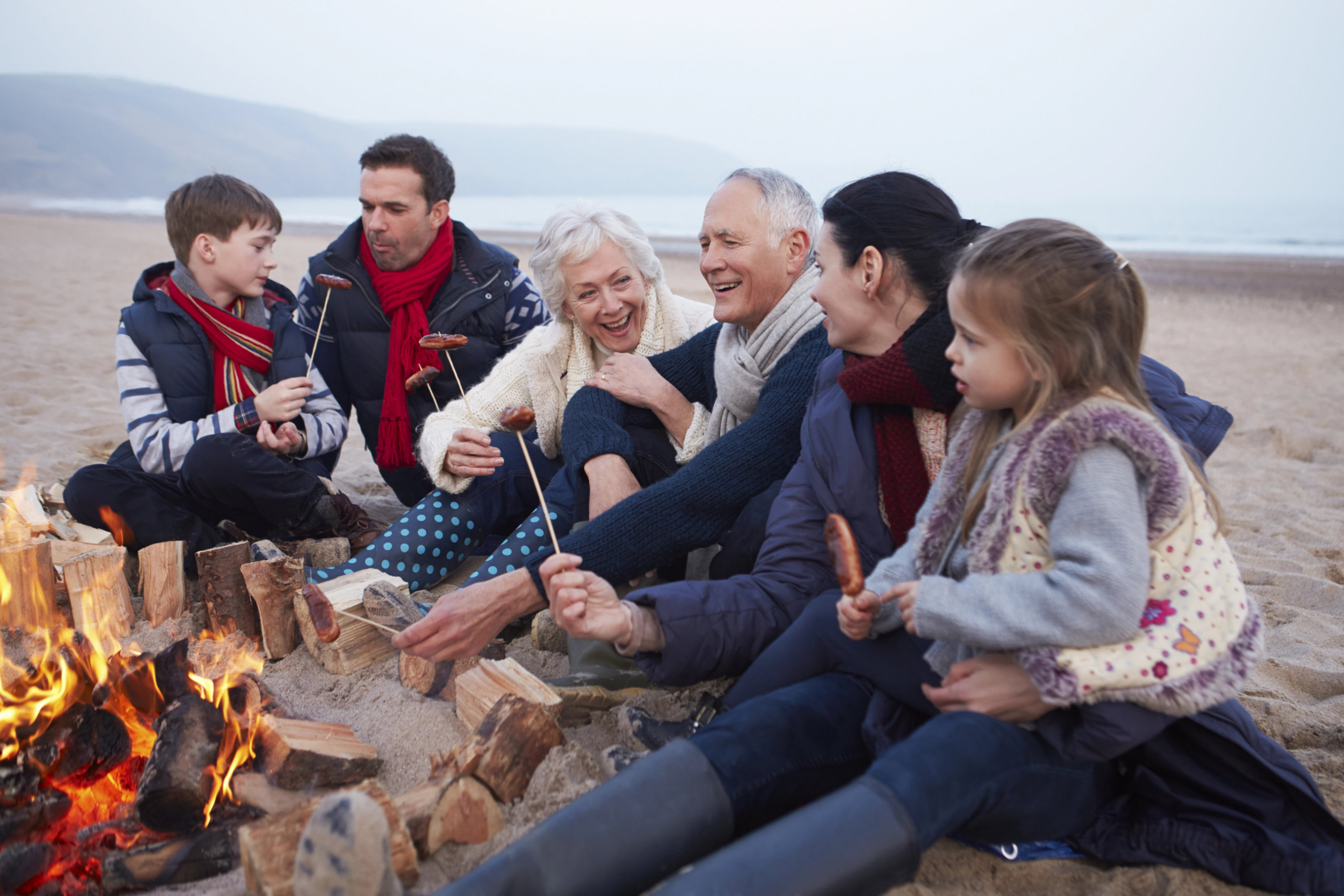 A family sitting around a fire on the beach