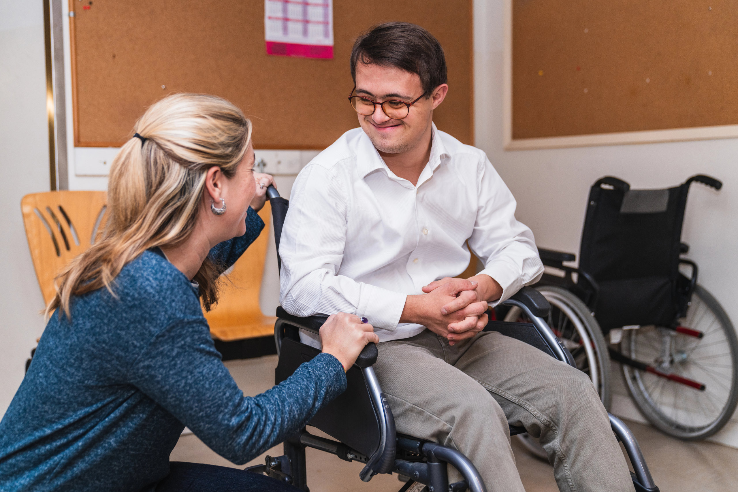 A woman speaking with a happy, smiling special needs man