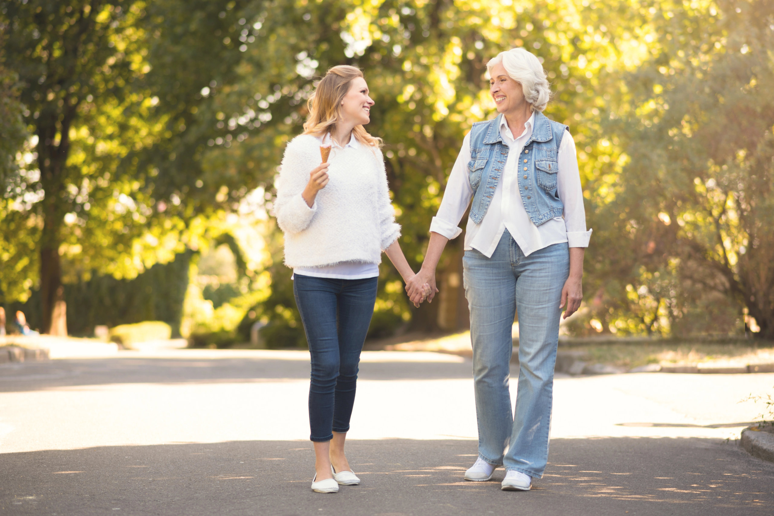 An older and younger women walking in a park